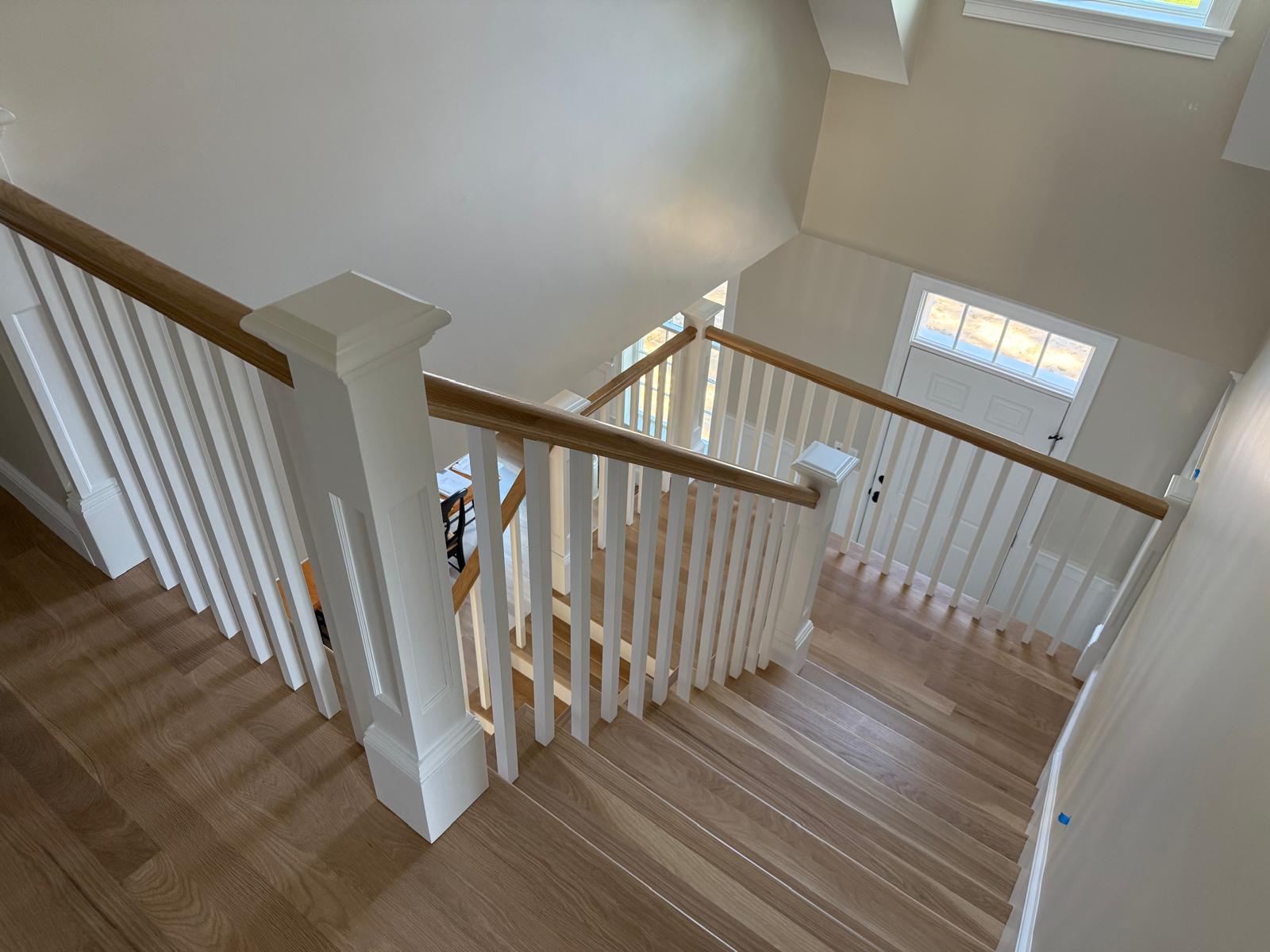 Custom staircase with white balusters and wood railings built by Miranda Finish Carpentry in New England
